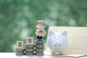 Businessman and stack of coins money on natural green background photo