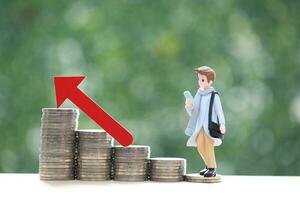 Business man standing on stack of coins money and red arrow graph on natural green background, investment and business concept photo