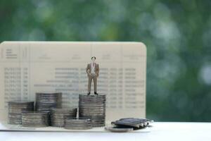Business man standing on stack of coins money on natural green background, investment and business concept photo