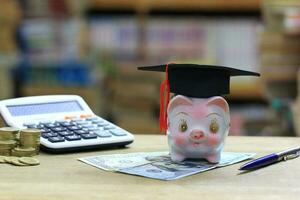 graduación sombrero en cerdito banco en estante para libros en el biblioteca habitación fondo, ahorro dinero para educación concepto foto