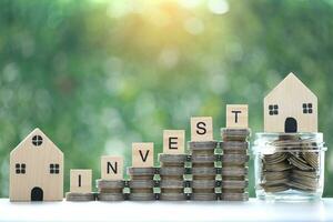 Mortgage,Model house and stack of coins money in the glass bottle on natural green background,Business investment and real estate concept photo