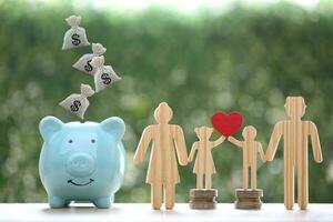 Model family with piggy bank and stack of coins money on natural green background,Save money for prepare in future and family finance concept photo