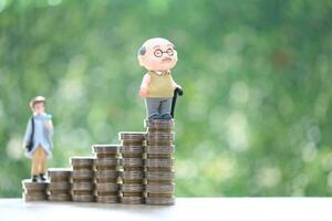 Retirement planning, Seniorman standing on stack of coins money on natural green background, Save money for prepare in future and pension retirement concept photo