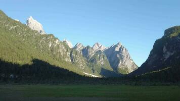 a mountain range with a green field and trees video