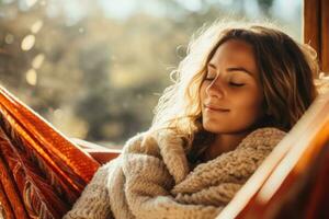 Person snuggling up with a blanket on a hammock in a cozy sweater photo