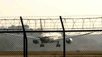 passageiro avião aterrissagem e frenagem. fumaça a partir de tocante a chassis dentro a luz de fundo. manhã voar A chegar às alvorecer video