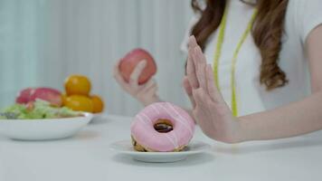 dieta y dieta. belleza cuerpo femenino delgado confundir donut. mujer con ropa de ejercicio logra el objetivo de pérdida de peso para una vida saludable, loca por la delgadez, cintura delgada, nutricionista. video