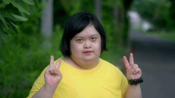 Asian young female  Down syndrome two thumb up smile while exercising in the park. video