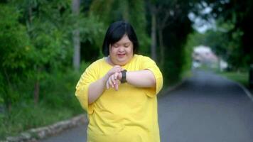 Asian girl with down syndrome look at the clock and rejoicewhile exercising in the park. video