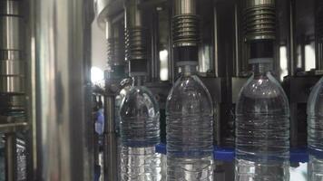 Water factory - Water bottling line for processing and bottling pure mineral water into blue bottles. Selective focus. video