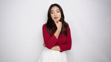 A confident Asian woman wearing red t-shirt, standing with arms folded, beauty pose and looking at the camera isolated over white background video