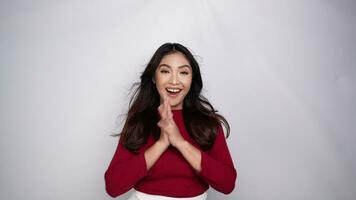 A young Asian woman with a happy successful expression wearing red top is cheering and supporting, isolated by white background video