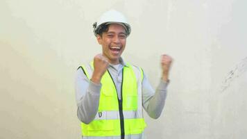 indonesiano lavoratore indossare veste e bianca casco sentire contento e Saluti. il metraggio è adatto per uso per ingegnere e sicurezza soddisfare media. video