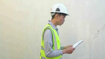 indonesio trabajador vestir chaleco y blanco casco cheque reporte luego tomar teléfono sensación contento. el imágenes es adecuado a utilizar para ingeniero y la seguridad contenido medios de comunicación. video
