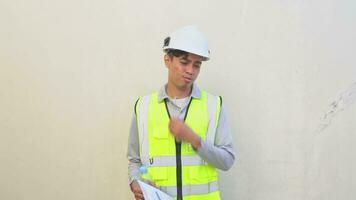 indonesisch Arbeiter tragen Weste und Weiß Helm prüfen Bericht dann Gefühl durstig. das Aufnahmen ist geeignet zu verwenden zum Ingenieur und Sicherheit Inhalt Medien. video