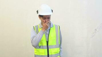 Indonesian worker wear vest and white helmet feel unwell and cough. The footage is suitable to use for engineer and safety content media. video