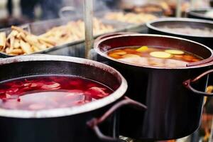 Beverages fruits and berries hot mulled wine in pots with steam in street food market. Generative AI photo