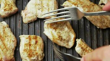 Cooking delicious roasted meat on a home electric grill. Pork delicacy. The cook turns the meat with forks. Close up. Top view. video