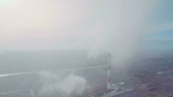 Aerial shot. Pipes with smoke industrial production, plant, air pollution. Dense thick smoke comes from industrial red-white pipes from a bird's eye view. Industrial zone smoke comes from the pipe video