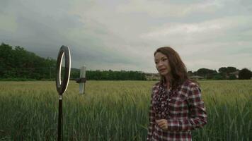 Blogger recording video at wheat field. Using ring lamp and smartphone outdoor