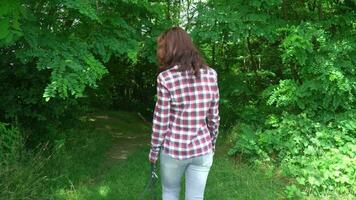 young woman wear checkered shirt and jeans walking with greyhound dog in summer forest. video