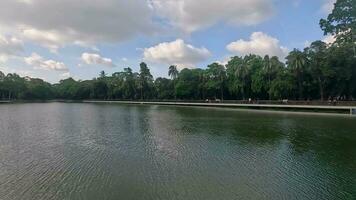 Beautiful central park view with a big lake and green trees. Scenic nature view inside a park with blue sky and clouds. Southeast Asian Park 4K footage and beautiful natural scenery. video