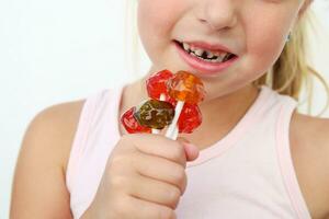 niño come caramelo. niña tiene caries en dientes. foto