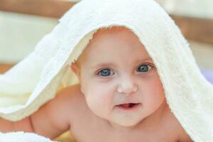 un pequeño bebé debajo un blanco toalla foto