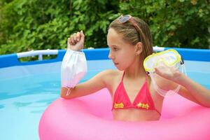 Girl chooses medical face mask or mask for scuba diving in pool. photo