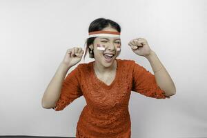 A young Asian woman with a happy successful expression wearing red kebaya and headband isolated by white background. Indonesia's independence day concept. photo