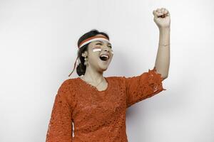 A young Asian woman with a happy successful expression wearing red kebaya and headband isolated by white background. Indonesia's independence day concept. photo