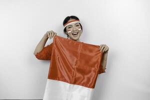 Happy smiling Indonesian woman wearing red kebaya and headband holding Indonesia's flag to celebrate Indonesia Independence Day isolated over white background. photo