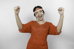 A young Asian woman with a happy successful expression wearing red kebaya and headband isolated by white background. Indonesia's independence day concept. photo