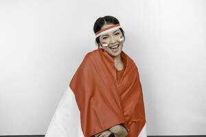 Happy smiling Indonesian woman wearing red kebaya and headband holding Indonesia's flag to celebrate Indonesia Independence Day isolated over white background. photo