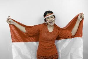 contento sonriente indonesio mujer vistiendo rojo kebaya y venda participación de indonesia bandera a celebrar Indonesia independencia día aislado terminado blanco antecedentes. foto