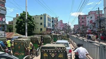 enorm trafik sylt i ett urban område. de dagligen liv av stad människor på en solig dag. trafik sylt och stad 4k antal fot med en skön blå himmel., brahmanbaria, bangladesh - juli 22, 2023 video