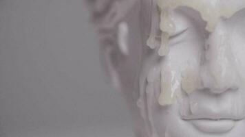 wax pouring over the face of an antique statue in slow motion video