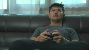 Asian young man having fun playing video games sit sofa at home.Asian young man having fun playing video games sit sofa at home.