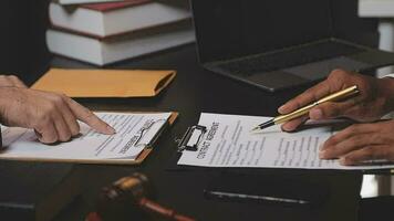 Business and lawyers discussing contract papers with brass scale on desk in office. Law, legal services, advice, justice and law concept picture with film grain effect video