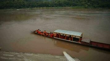 luangprabang lao-july19,2023 group of wat xiangthong monk in luangprabang taking into mekong river boat crossing to oposite river site at morning video