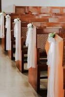 A church aisle with a white ribbon and flowers photo