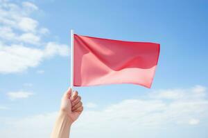 Hand holding red flag against blue sky photo