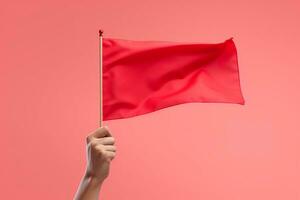 Hand holding red flag against blue sky photo