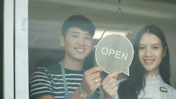 Happy Coffee Shop owner in an apron turning open sign board on glass door. Small business owner opening a small business. photo