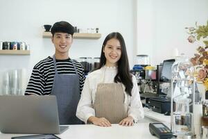 Two young managers or shop owners having some discussion working on a laptop at the counter of the shop or cafe. photo