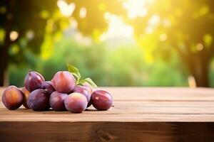 Wooden table top on blurred background of orchard with plums photo