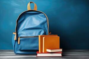 School bag and textbooks in front of a blue background. Back to school concept photo