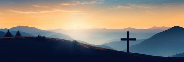 Silhouette of a cross on a hill in a mountain landscape at sunset. photo