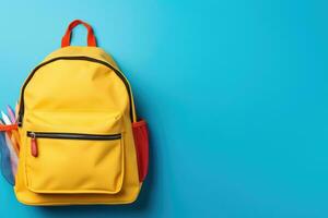 School bag and textbooks in front of a blue background. Back to school concept photo