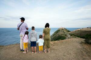 Family of five standing on the top of the mountain looking at the sea. Cape Emine, Black sea coast, Bulgaria. photo